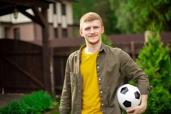 Feliz ventilador de fútbol masculino con pelota de fútbol mira a la cámara con sonrisa, espacio de copia —  Fotos de Stock