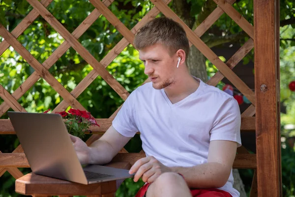 Hombre freelancer en auriculares funciona en el ordenador portátil se comunica en línea, la navegación por la red — Foto de Stock