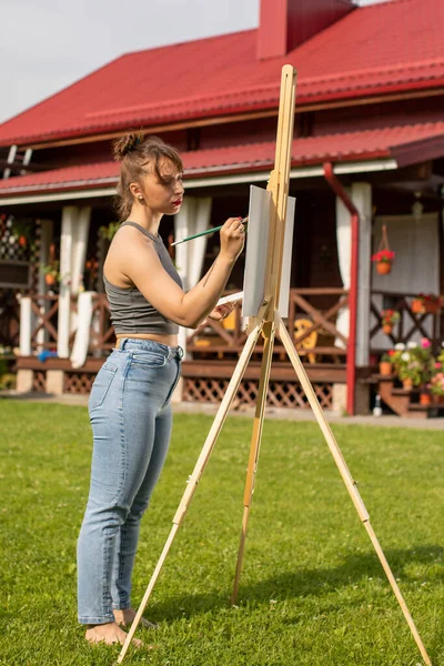 Joven hermosa mujer pintura cuadro en caballete en préstamo en el campo, pasatiempo — Foto de Stock