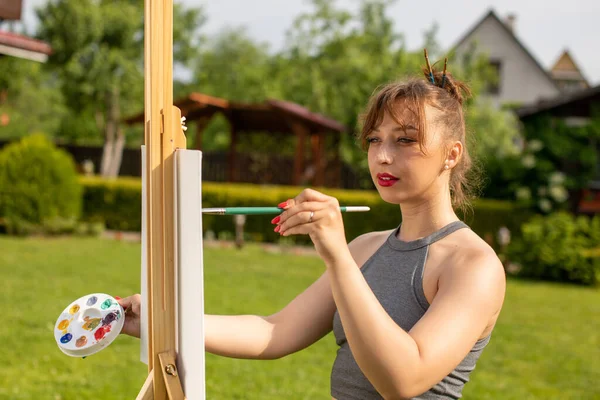 Γυναίκα καλλιτέχνης ζωγραφική εικόνα για easel για δάνειο στο πάρκο, υπαίθρια δραστηριότητα — Φωτογραφία Αρχείου