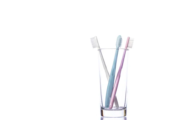 Three toothbrushes in transparent glass isolated on white background. Copy space — Stock Photo, Image