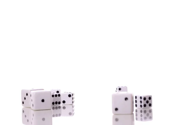 不同尺寸的分散的白色骰子反映在桌子表面上 — 图库照片