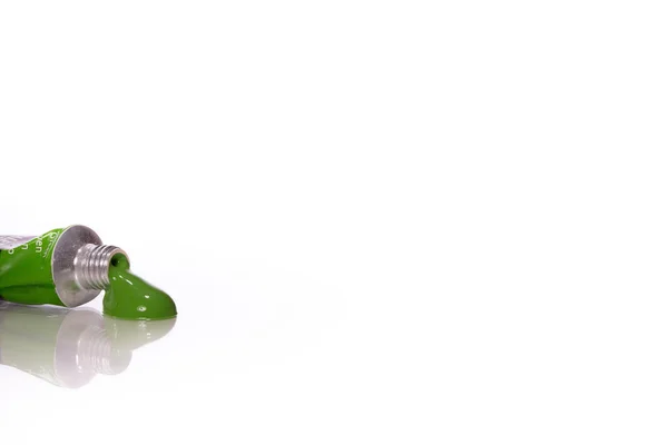 Стиснутий акриловий масляний фарба для трубки зеленого кольору, відображений у скляній поверхні столу — стокове фото
