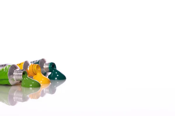 Drie geperste verfbuizen groen en geel in glas gereflecteerd — Stockfoto