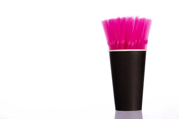 粉红塑料稻草在黑色纸杯隔离在白色背景。复制空间 — 图库照片