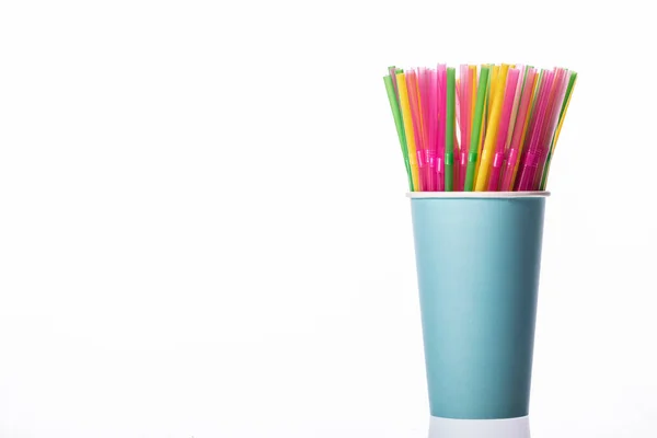 Pajitas para beber de plástico de color en una taza de papel azul aislada sobre fondo blanco — Foto de Stock