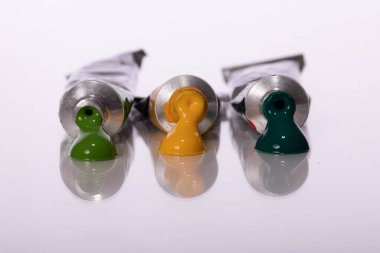 Açık, koyu yeşil ve sarı akrilik boya tüpleri beyaz arkaplanda izole edilmiş.