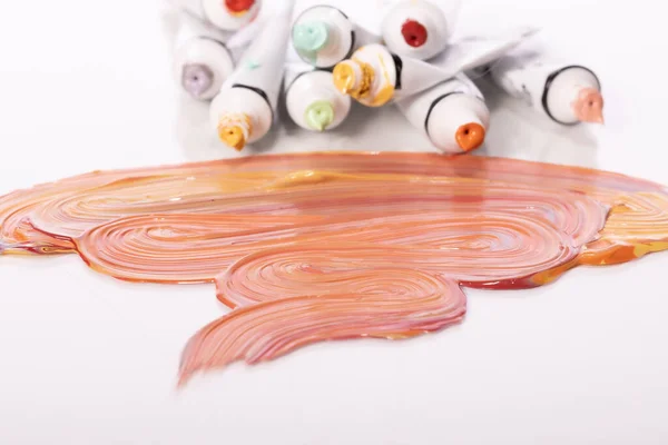 Tubos abiertos de pintura acrílica de colores tumbados en la mesa de vidrio junto a pinceladas — Foto de Stock