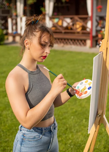 Jovem bela mulher pintura quadro no cavalete, ao ar livre atividade relaxante — Fotografia de Stock