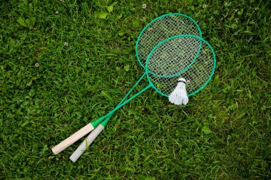 Badminton raketleri ve servis horozu yeşil çimlerin üzerinde, açık hava oyunu