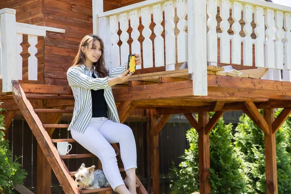 Elegante joven mujer alegre con perro york haciendo retrato selfie en escalones de madera — Foto de Stock