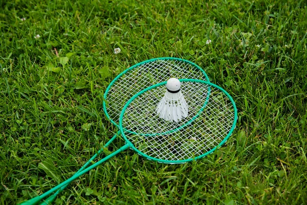 Close up badminton rackets shuttlecock on green grass outdoors, sport activity