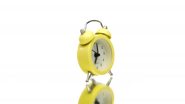 Pequeno relógio de alarme vintage amarelo girando isolado no fundo branco — Vídeo de Stock