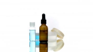 Kozmetik şişe sıvıları beyaz arka planda dönüyor, vücut yağı doğal kremi.