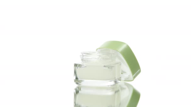 Vasetto cosmetico in vetro per la cura della pelle con crema idratante ruotante su sfondo bianco — Video Stock