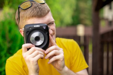 Genç yaratıcı fotoğrafçının yakın plan portresi anlık kamerayla fotoğraf çekiyor.