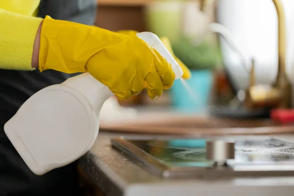 Visão de perto da pessoa em luvas de borracha limpeza bancada de cozinha usando spray — Fotografia de Stock