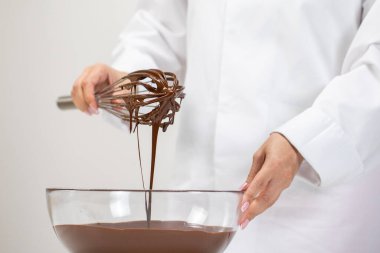 Yumuşak eritilmiş sütlü çikolatayla çırpılmış cam kaseyi karıştırıyorum. Yakın çekim.