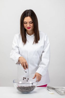 Güzel bir şekerci el yapımı çikolata yapıyor, siyah çikolata damlaları döküyor.