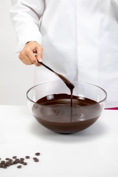 Primo piano chef mescolando versando cioccolato fondente amaro fuso su sfondo bianco — Foto Stock