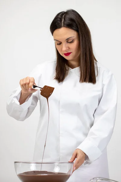 Beautiful pastry-cook pouring dark melted chocolate isolated on white background