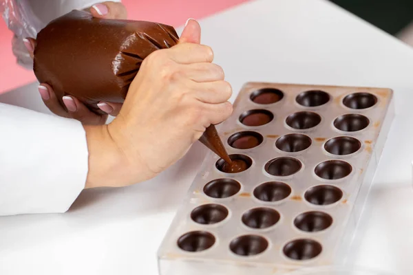 Chocolatier gießt Karamellfüllung in Schokoladenform und bereitet handgemachte Bonbons vor — Stockfoto