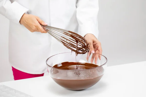 Mani di cioccolato femminile mescolando cioccolato fondente fuso con frusta isolata — Foto Stock