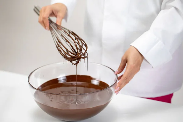 Chef sbattere il cioccolato fuso in una ciotola di vetro utilizzando la vecchia frusta filo vintage — Foto Stock