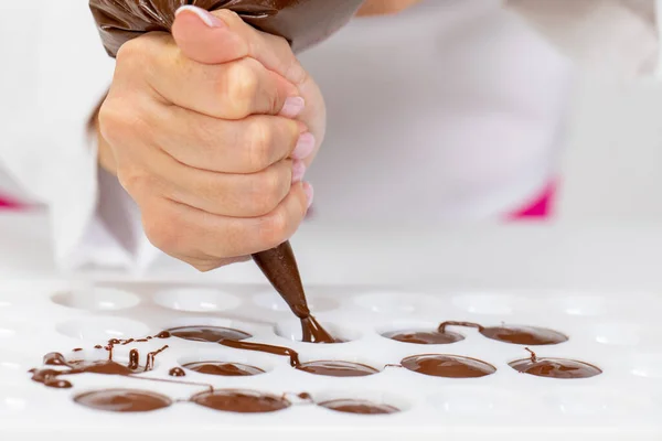 Primo piano cioccolatiere riempimento stampo pasticceria plastica con cioccolato fuso — Foto Stock