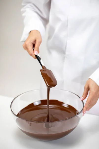Mano di pasticciere femminile mescola cioccolato svizzero fuso al latte in una ciotola di vetro — Foto Stock