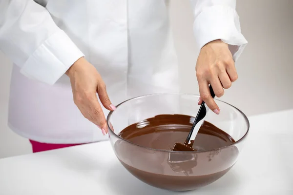 Nahaufnahme Chocolatier rührt dunkle geschmolzene Schokolade in Glasschale weißer Hintergrund — Stockfoto