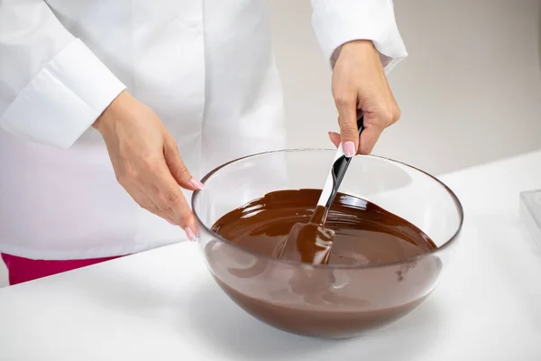 Mano di cioccolato femminile mescola cioccolato fondente fuso in una ciotola di vetro — Foto Stock