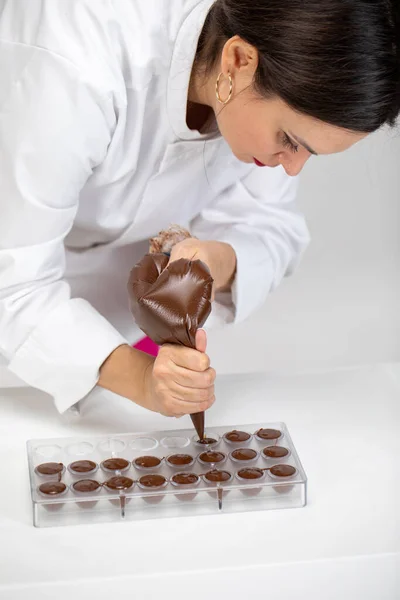 Chef gießt dunkle geschmolzene Schokolade in Form mit Teigtasche, handgefertigte Bonbons — Stockfoto