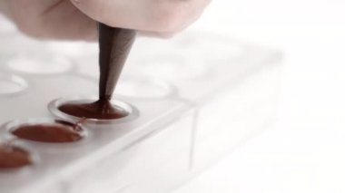 Koyu çikolatayı pasta torbasıyla plastik kalıba döküyorum, yavaş çekim.