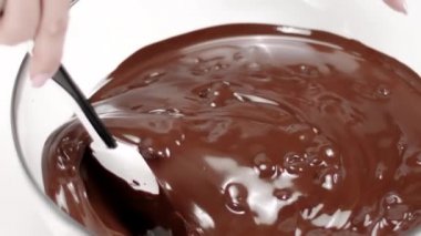 Yakın çekim karıştırma karıştırma karıştırma koyu erimiş çikolata cam kasede, yavaş çekim