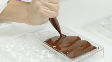 Koyu çikolatayı elmas şekilli kalıba döküyorum, yavaş çekimde.