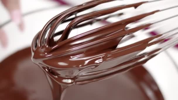 Batidor tomado de chocolate negro caliente de cerca. derretido flujo de chocolate por mo lento — Vídeos de Stock