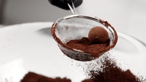 Chocolatier de primer plano haciendo trufa tradicional de chocolate negro espolvoreada con polvo — Vídeo de stock