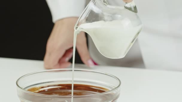 Close-up gieten melk in donkere organische gesmolten chocolade, het maken van chocolade crème — Stockvideo