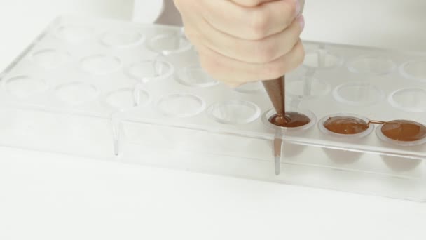 Primo piano cioccolatiere spremitura crema fondente per caramelle al cioccolato con sacchetto di pasticceria — Video Stock