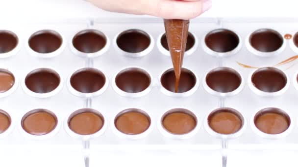 Chocolatier derramando caramelo enchimento no molde de chocolate preparando doces slow mo — Vídeo de Stock