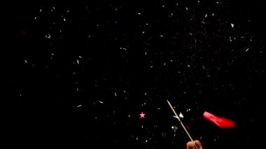 Kırmızı balon altın sarısı süslemelerle patlar ve yıldızlar yavaş çekim siyah üzerine izole edilir.
