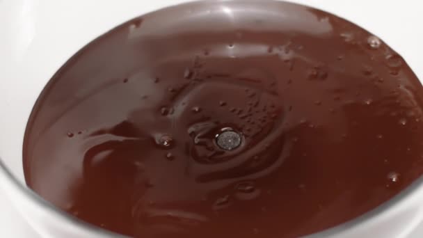Chocolate chips couverture callets fall in bowl of melted dark chocolate slow mo — Stock Video