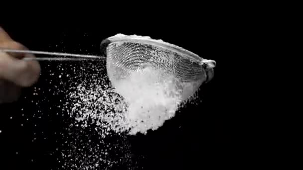 シェフは黒で隔離されたふるい遅い動きで粉砂糖または小麦粉をふるいにかける — ストック動画