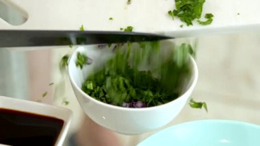 Şef, Japon yemeği pişiren dilimlenmiş soğan kasesine doğranmış maydanoz ekliyor.