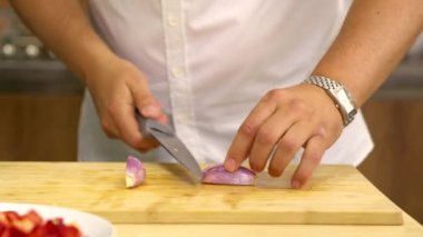 Amatör şef ev mutfağında soğan doğrama tahtasıyla keser.