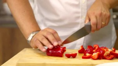 Aşçı mutfakta çan biberi doğruyor. Evde yemek pişiriyor.