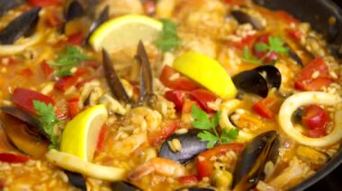 Deniz ürünleri, midye, kalamar ve maydanozlu paella pişiriyorum. Bulaşık ağızları, yükselen buhar