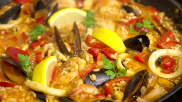 Memasak paella dengan makanan laut, kerang, cumi-cumi, peterseli. piring gurgles, uap naik — Stok Video