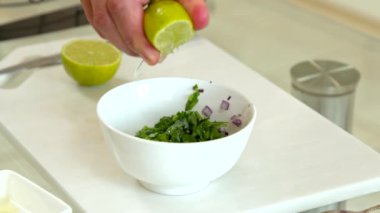 Kapalı erkek aşçı taze limonu doğranmış yeşilliklere sıkıştırıyor vegan salatası pişiriyor.